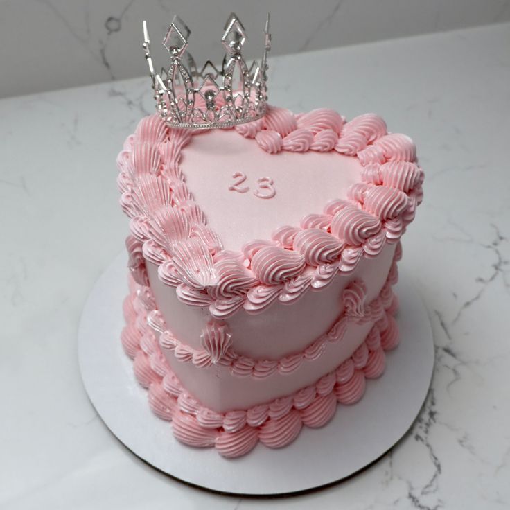 a pink heart shaped cake with a crown on top