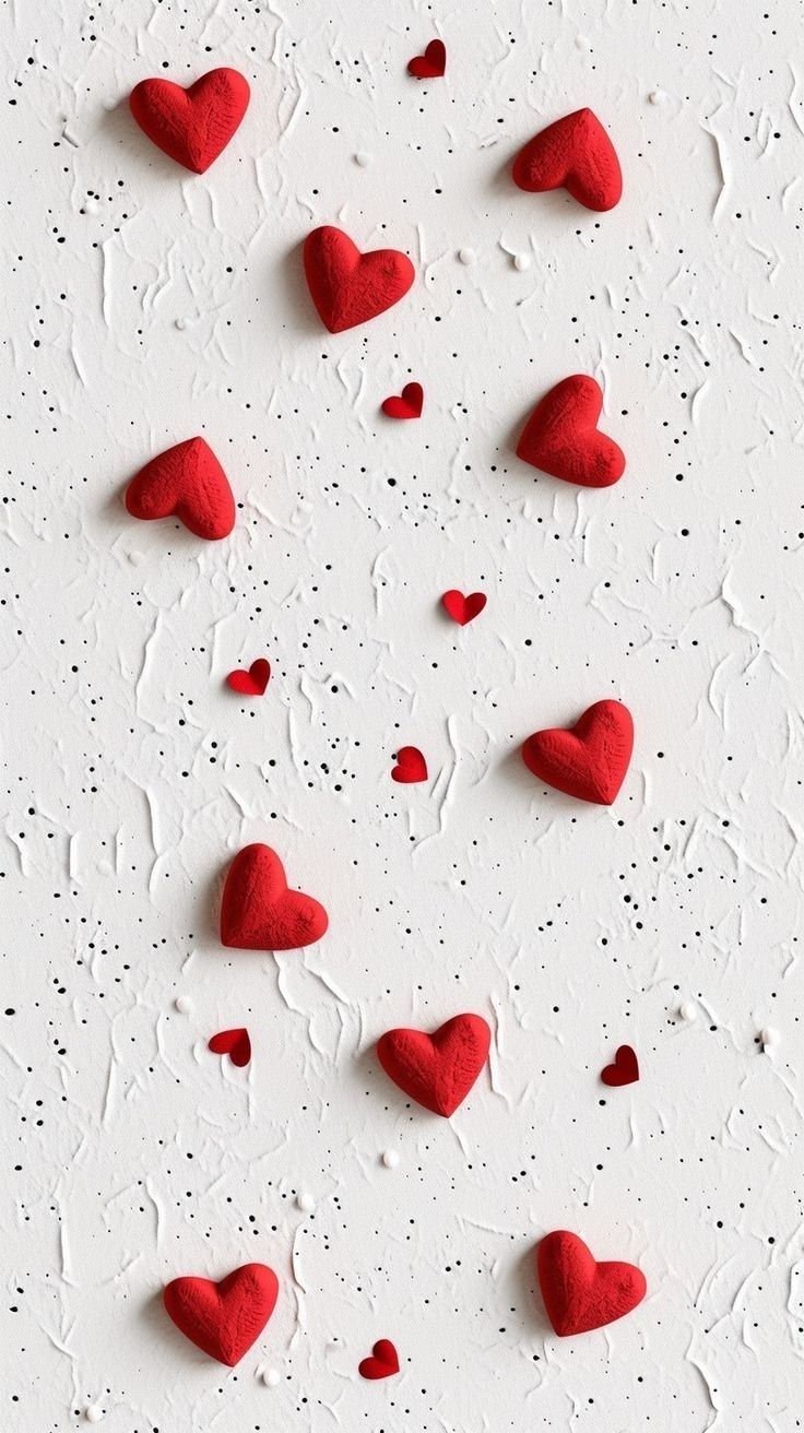 some red hearts on a white surface with drops of water and sprinkles