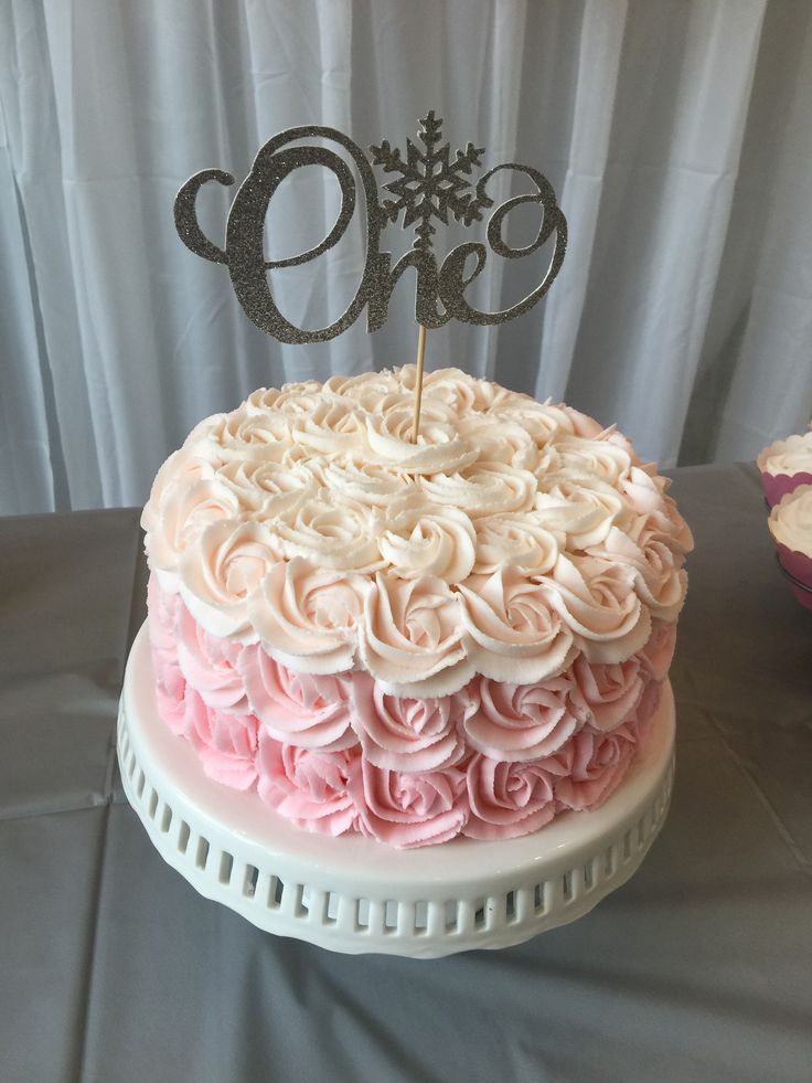 a cake with pink and white frosting sitting on top of a table