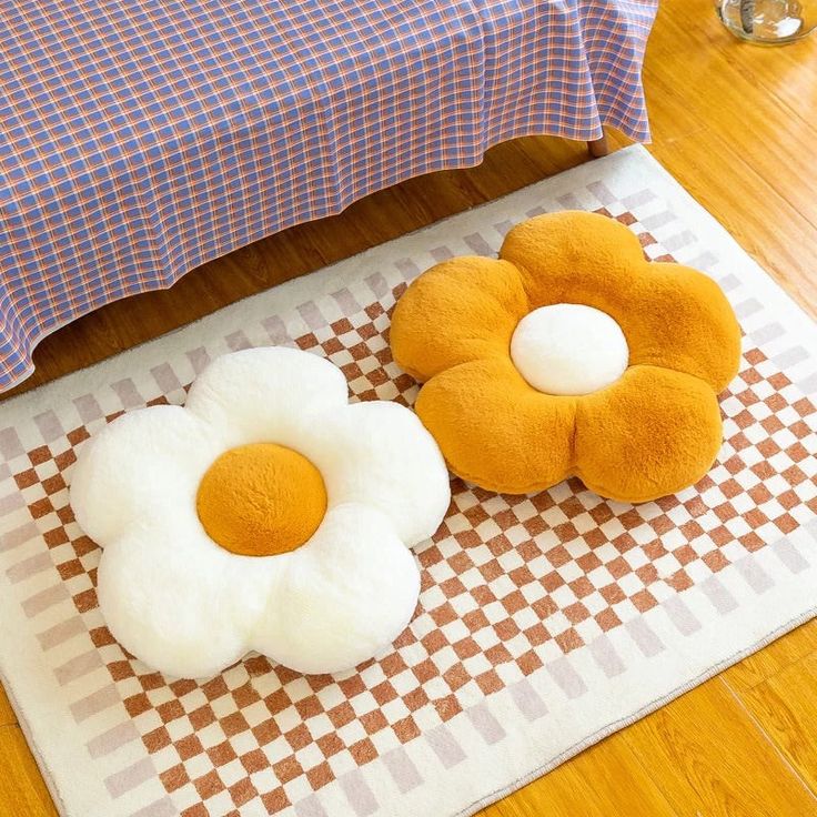 two fried eggs are sitting on the floor next to a bed with checkered bedspread