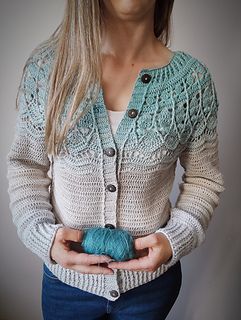 a woman is holding a ball of yarn in her hands while wearing a cardigan