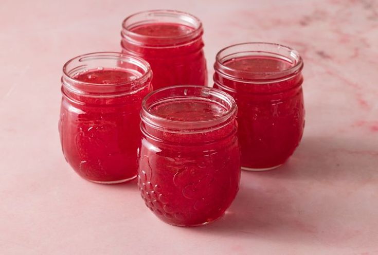 four jars filled with red liquid sitting on top of a table