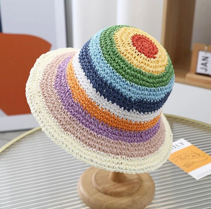 a multicolored crocheted hat sitting on top of a wooden stand with a price tag