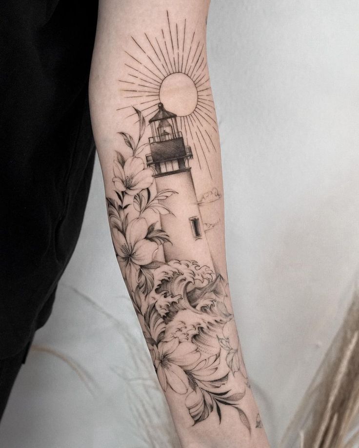 a woman's arm with a lighthouse and flowers on it