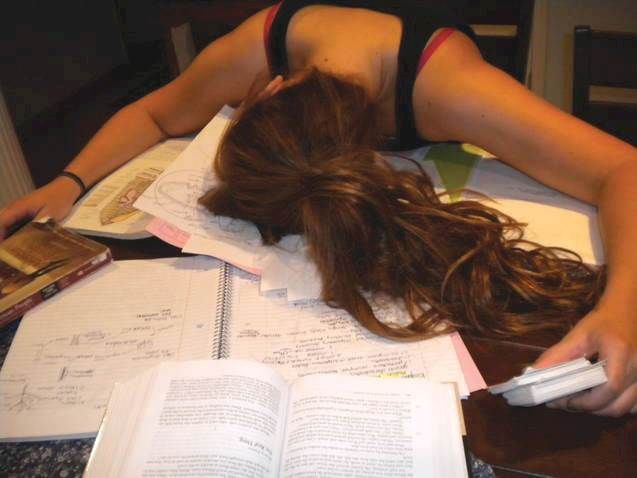 a woman is laying down with her head on an open book and holding a remote control