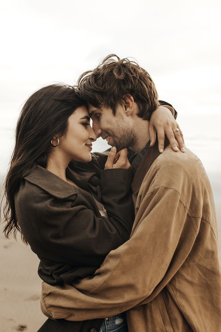 a man and woman embracing each other on the beach