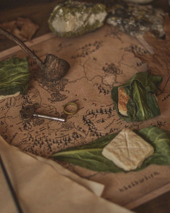 an old map with leaves, rocks and a pipe on the table next to it