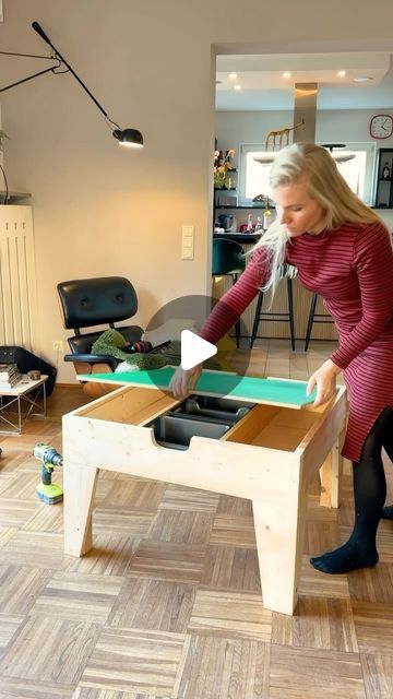 a woman in a red dress is playing air hockey on a wooden table with drawers