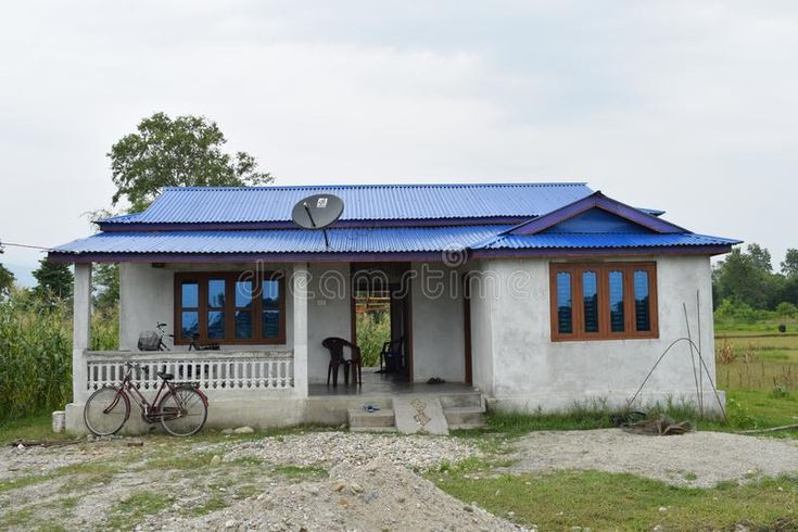 a small white house with blue roof and bicycle parked outside