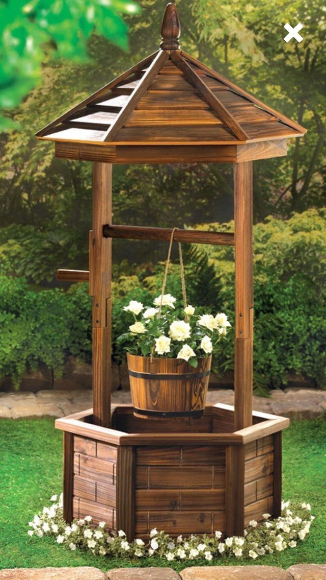 an outdoor wooden gazebo with flowers in the potted planter and on the ground