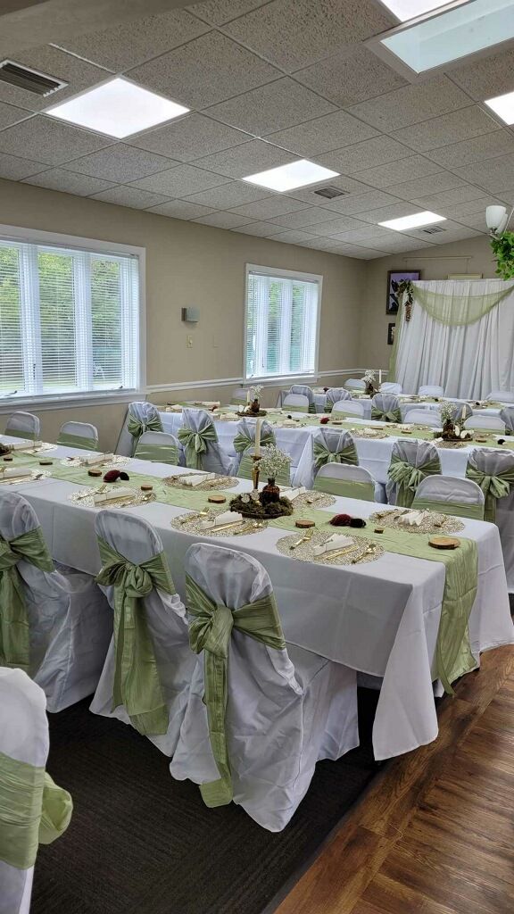 a banquet room set up with tables and chairs covered in white tablecloths, green sashes and bows