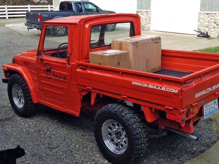 a red truck with a box on the back and a black cat sitting next to it