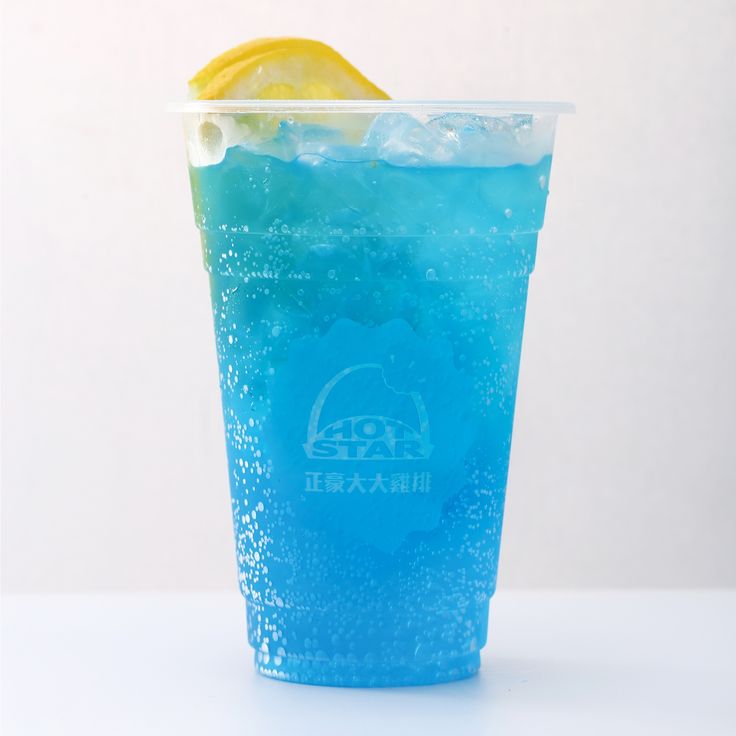 a blue drink with ice and lemon wedges