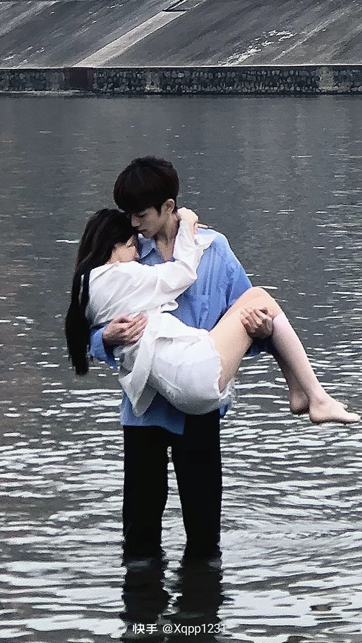 a man holding a woman in his arms while standing in the middle of a body of water