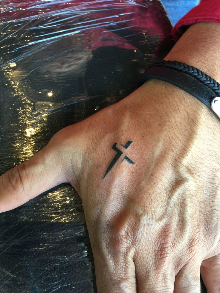 a person's hand with a cross tattoo on it