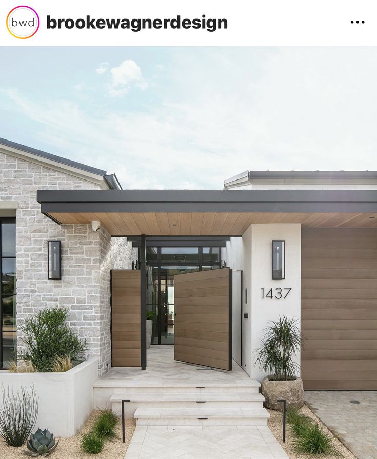 the front entrance to a modern home with wooden doors