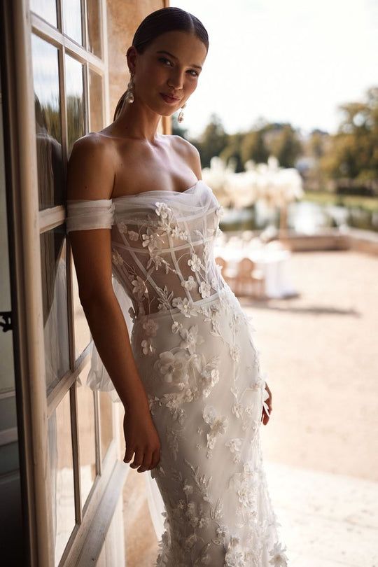 a woman in a wedding dress leaning against a wall with her hand on the door