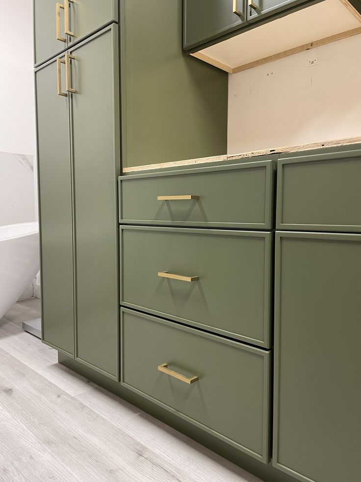 an empty bathroom with green cabinets and white bathtub