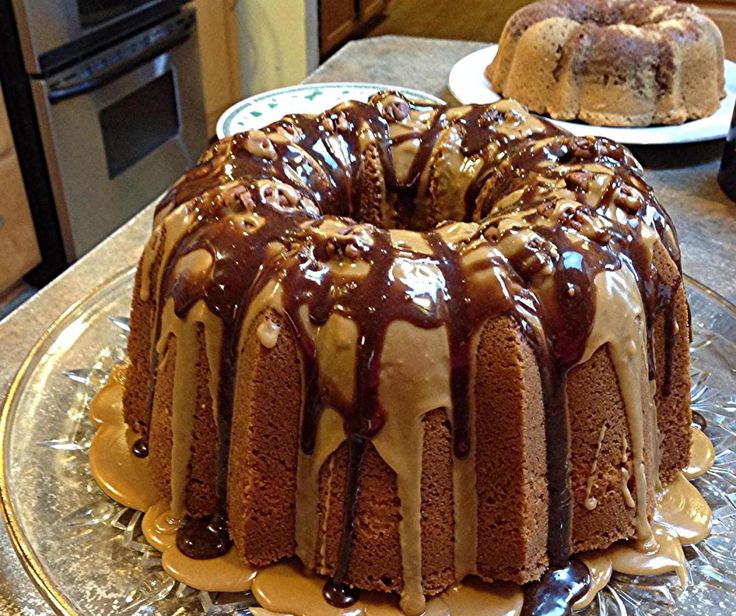 two bundt cakes sitting on top of a glass cake plate covered in frosting