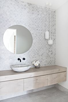 a bathroom with a sink, mirror and vase on the counter in front of it