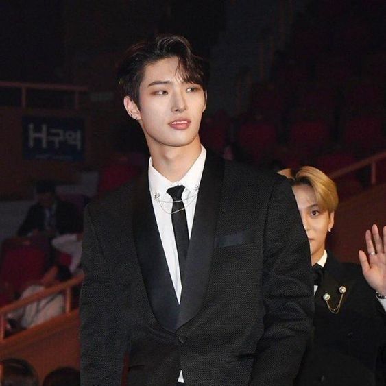 a young man in a suit and tie waves to the crowd as he stands next to him