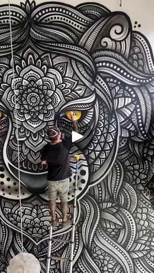 two men are painting a large black and white mural