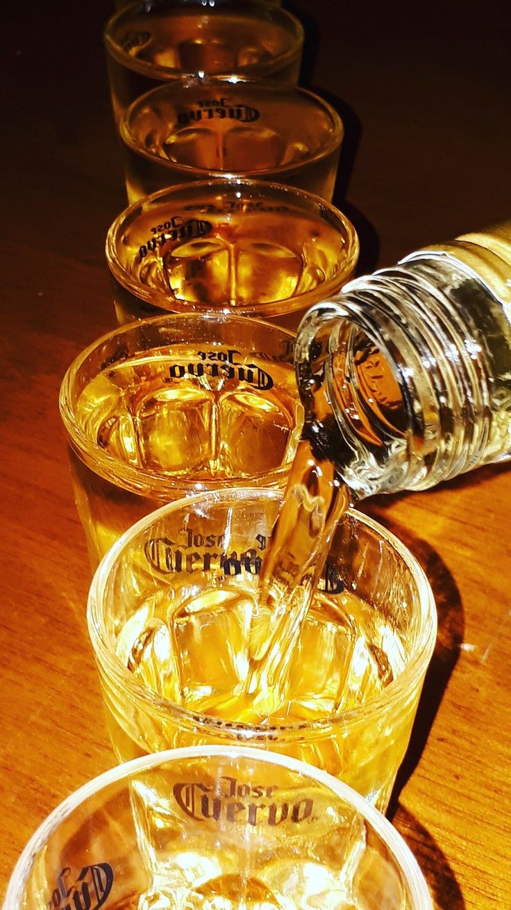 several glasses filled with liquid sitting on top of a wooden table