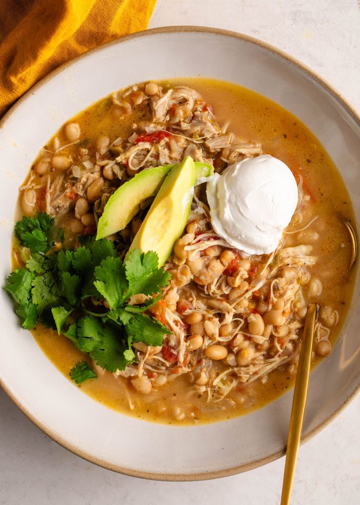 a white bowl filled with beans, avocado and sour cream on top of a table