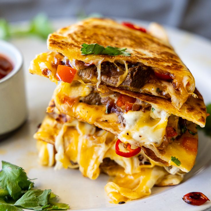 three quesadillas stacked on top of each other with sauce and garnishes