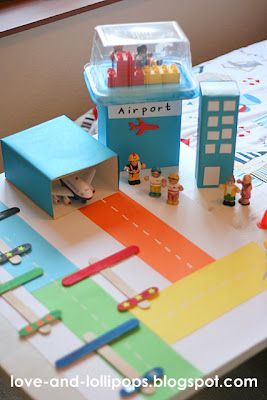 the table is covered with colorful paper and toy buildings, including an airport set up on it