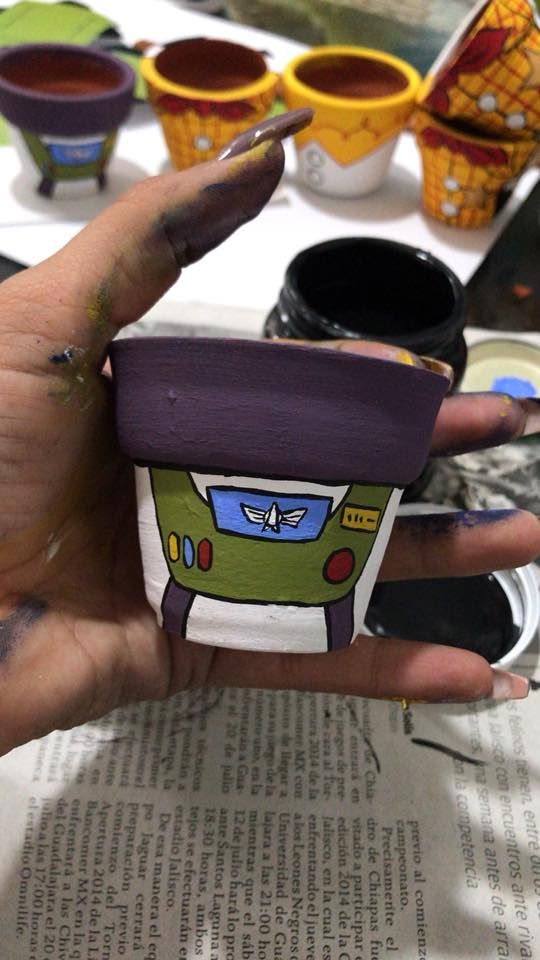 a person holding up a small cup in front of some other cups on a table