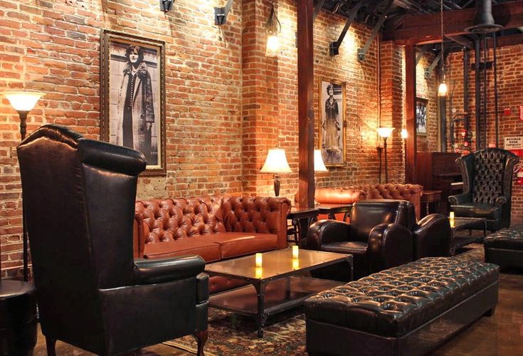 a living room with couches, chairs and tables in front of a brick wall