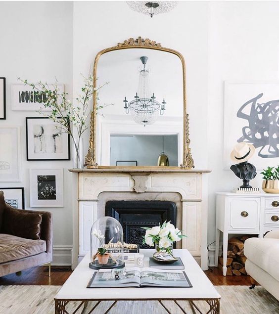 a living room filled with furniture and a large mirror on the wall over a fireplace