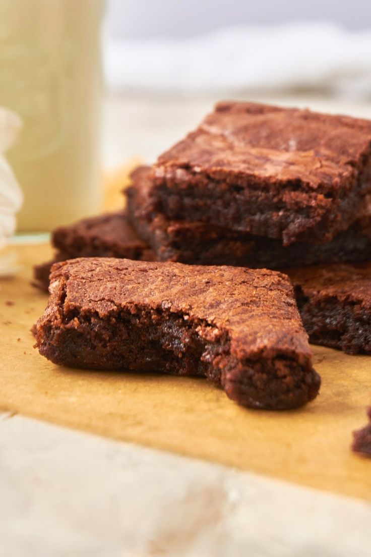 some brownies sitting on top of a wooden cutting board next to a glass of milk