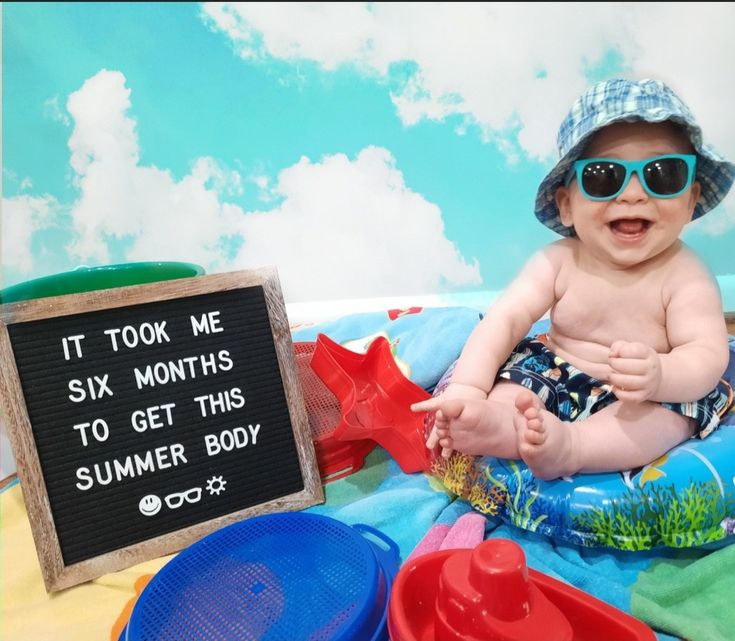 a baby wearing sunglasses sitting on top of a blue and green blanket