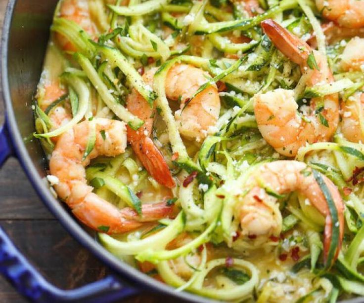 zucchini noodles with shrimp and herbs in a blue pan on a wooden table