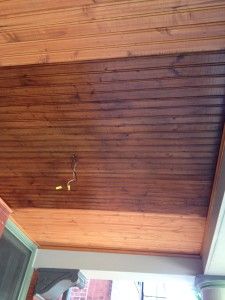 the ceiling is covered with wood planks and has a small lizard crawling on it