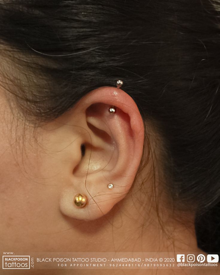 a woman's ear with two piercings on top of her head and one behind the ear