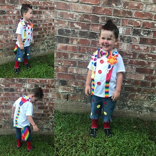 a little boy standing in front of a brick wall wearing a clown costume and smiling at the camera