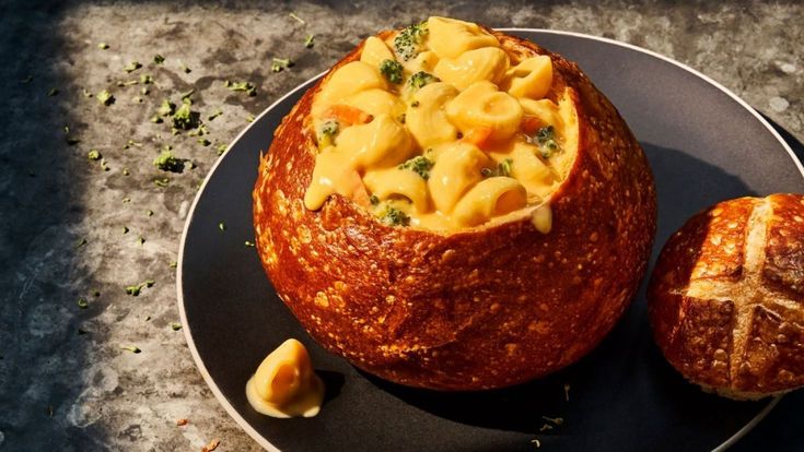 a plate that has some kind of food in it on top of a table next to bread