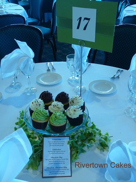 cupcakes are sitting on a glass plate at the center of a banquet table