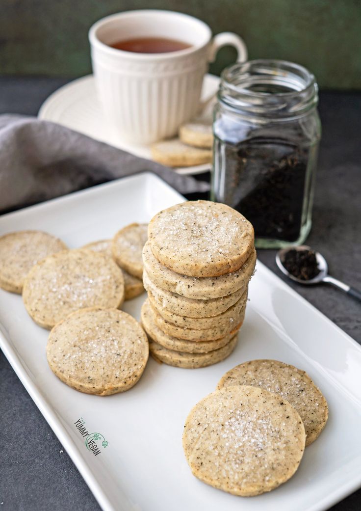 a white plate topped with cookies next to a cup of tea