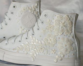 a pair of white sneakers with flowers and pearls on the side, all in white