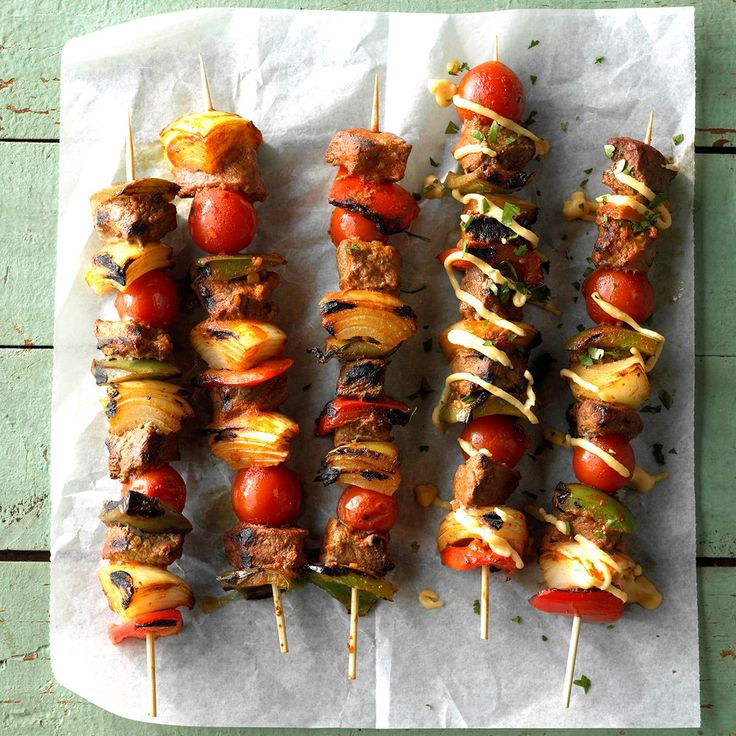 several skewers of meat and vegetables on a piece of paper