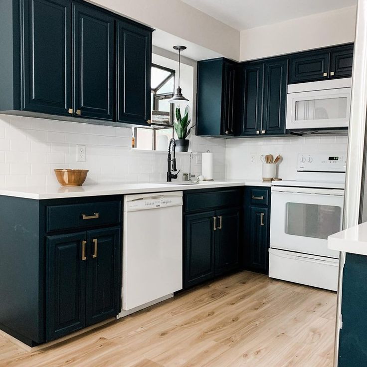 a kitchen with black cabinets, white appliances and wood floors is pictured in this image