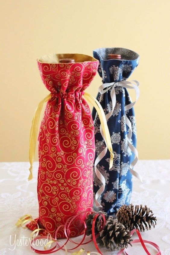 two wine bags sitting on top of a table next to pine cones and twine