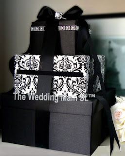 a black and white wedding cake sitting on top of a table next to a bouquet