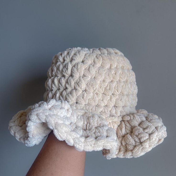 a white crocheted hat on someone's arm, against a gray background