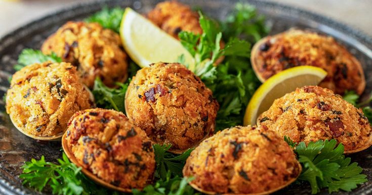 some crab cakes are on a plate with lemon wedges