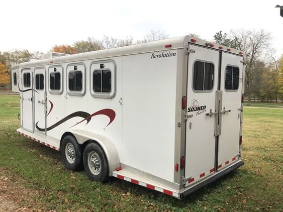 a horse trailer is parked in the grass